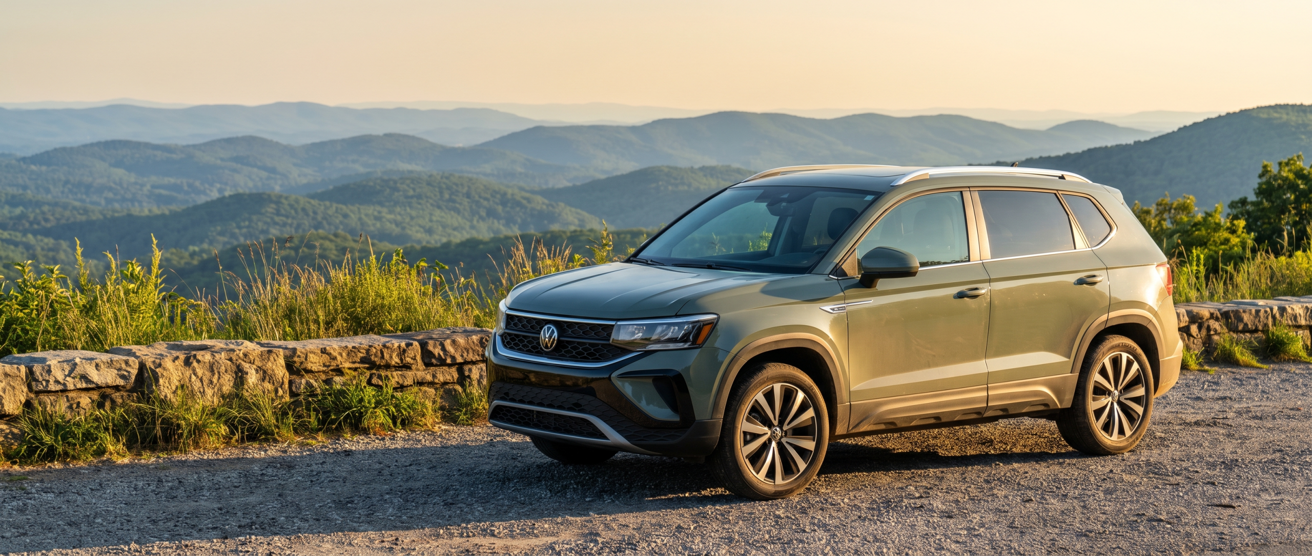 A 2026 Volkswagen Taos parked at a scenic Upstate South Carolina overlook with Blue Ridge foothills visible in the background, late-summer afternoon light, subtle green hills, no other vehicles
